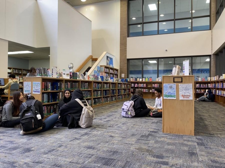 Students gather between library shelves during lunch. 