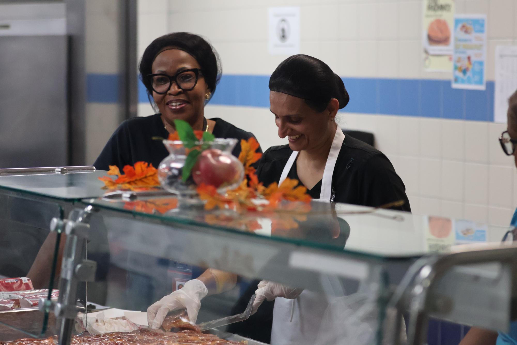 Jasmin Momin and Abiodun Alashe scoop warm cinnamon rolls into individual paper trays for breakfast. Students can also pick up a yogurt or fruit juice to have in the Commons before first period.