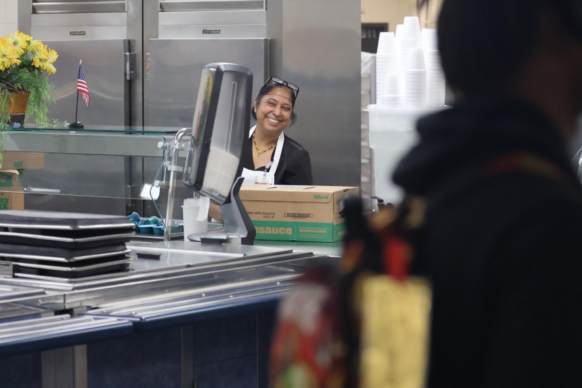 Sabitri Pokharel stacks applesauce cups in the open fridges in the lunch line. Blue raspberry Zee Zee's are a longtime cafeteria staple.