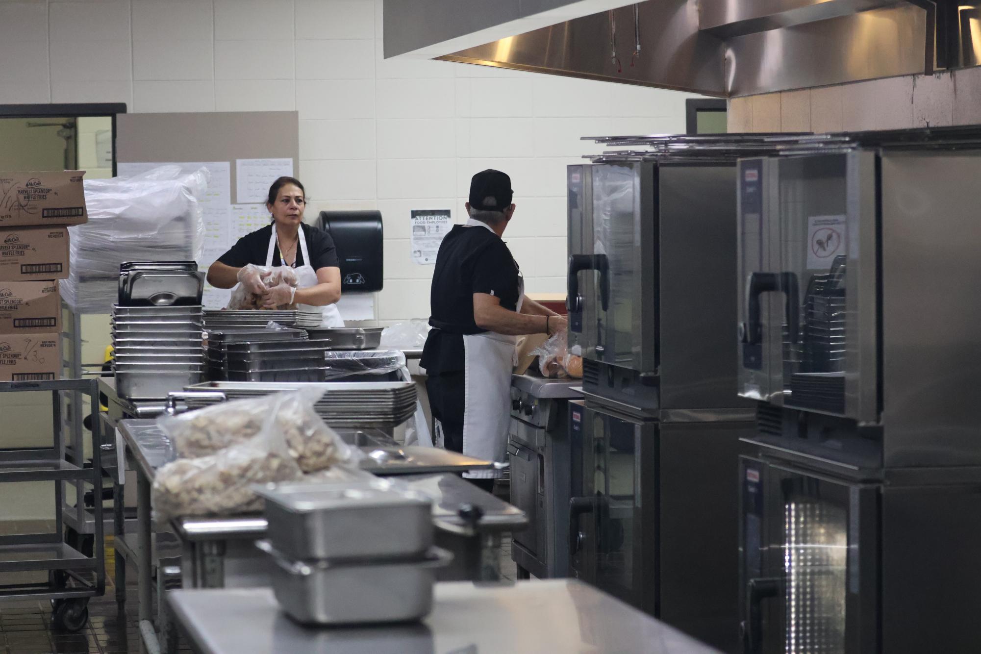 In the back kitchen, Shameela Rashed and Anton Sakhleh unwrap bags of hamburger buns. Though lunch items aren't made from scratch anymore, assembly still requires careful attention to detail.