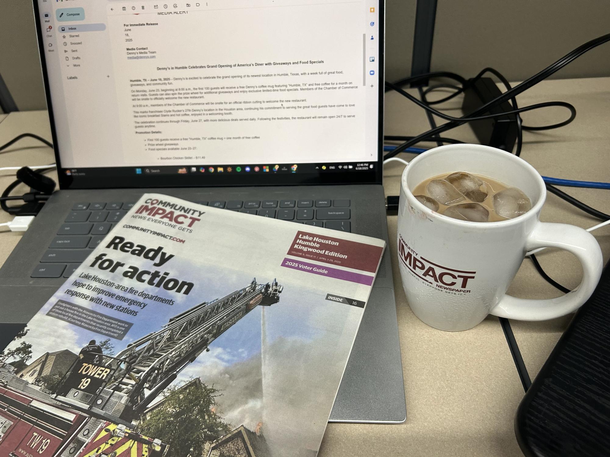 Hu's cubicle at Community Impact, with a cup of iced coffee and a recently printed Lake Houston paper.