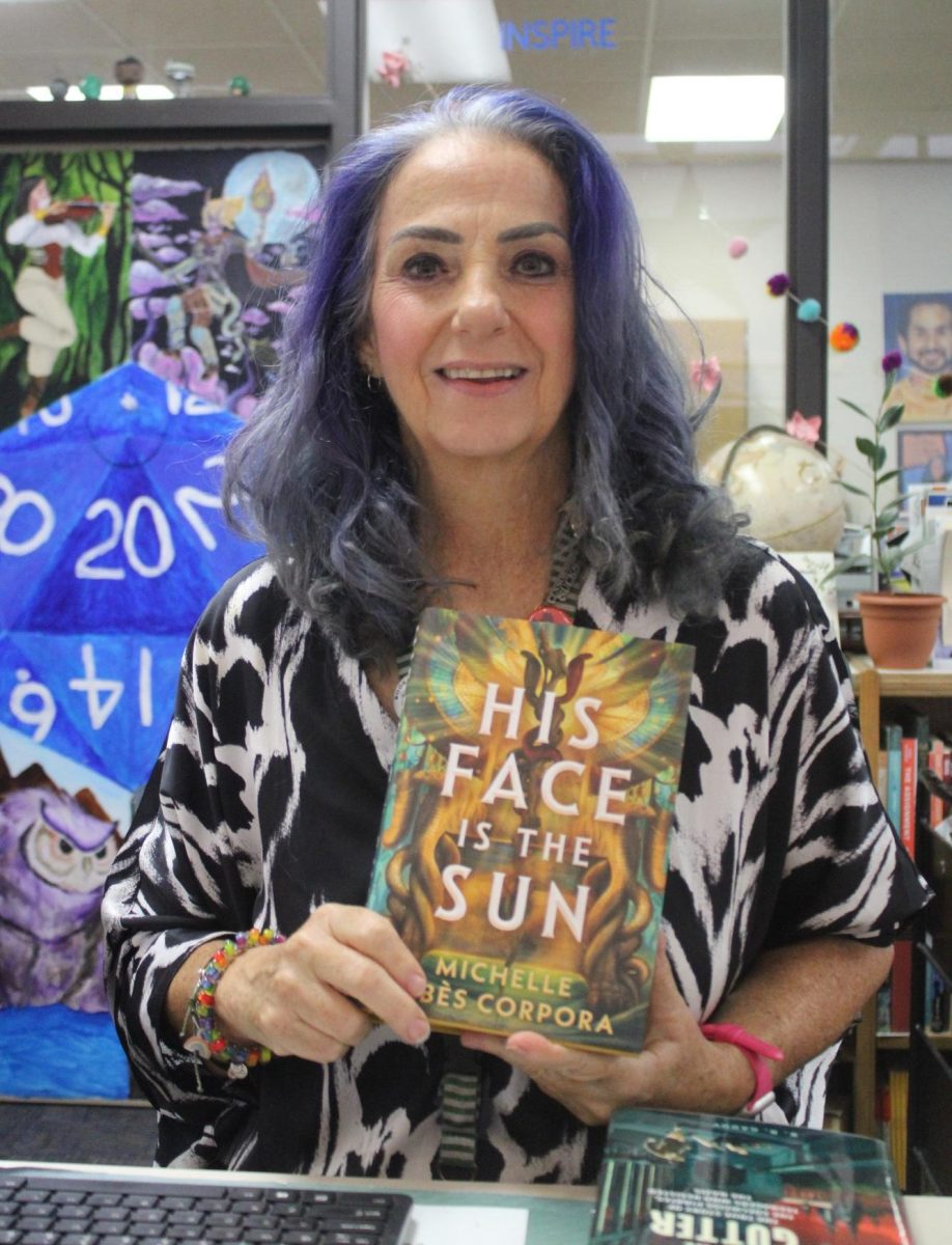 Librarian Marion Brennan holding one of her favorite summer reads, "His Face is the Sun."