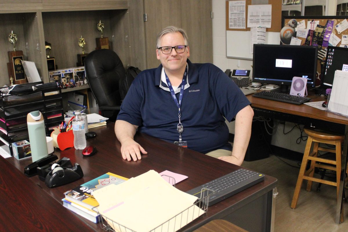 Debate and Professional Communications teacher Vincent Beard sitting at his desk.