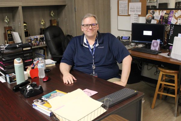 Debate and Professional Communications teacher Vincent Beard sitting at his desk.