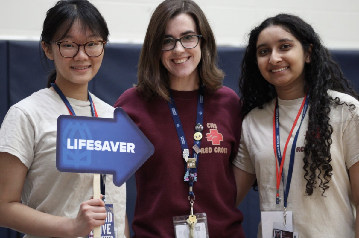 Rhea Desai (right) with sponsor Caitlin Zuber (middle) and Daphne Tu (left), pointing a “Lifesaver” sign at Zuber.