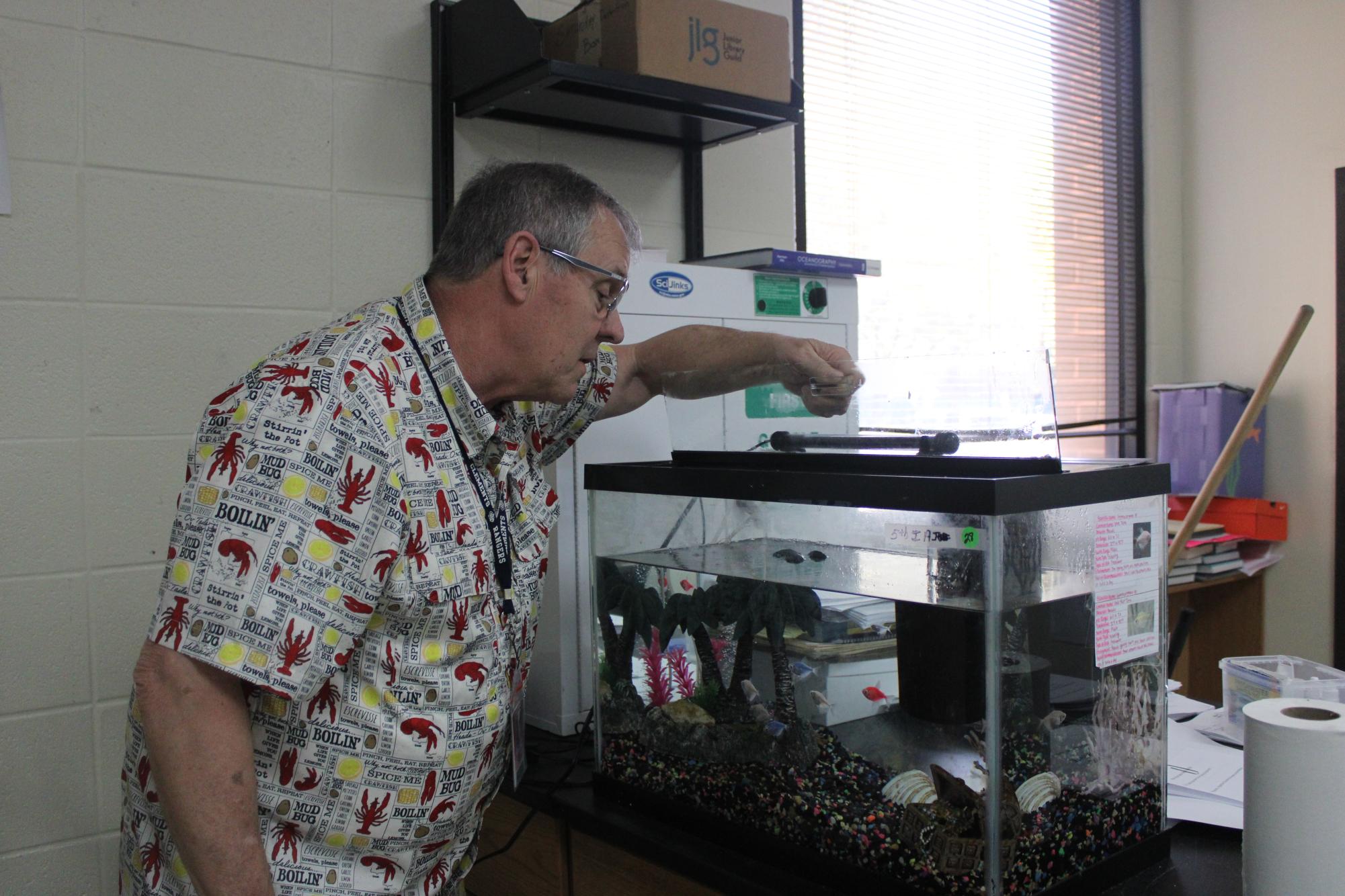 Aquatic Science teacher Mark Schubert checks on one of the classroom aquariums, which houses several live fish.