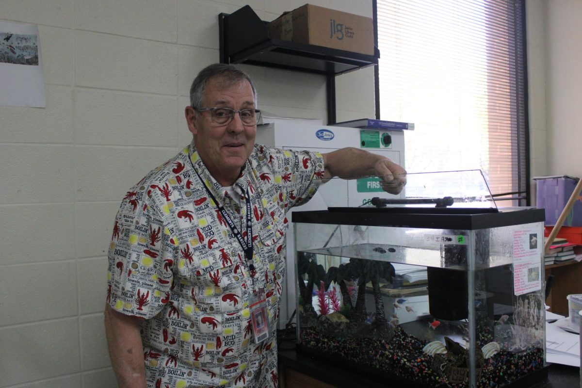 Aquatic Science teacher Mark Schubert demonstrates hands-on tank maintenance for students.